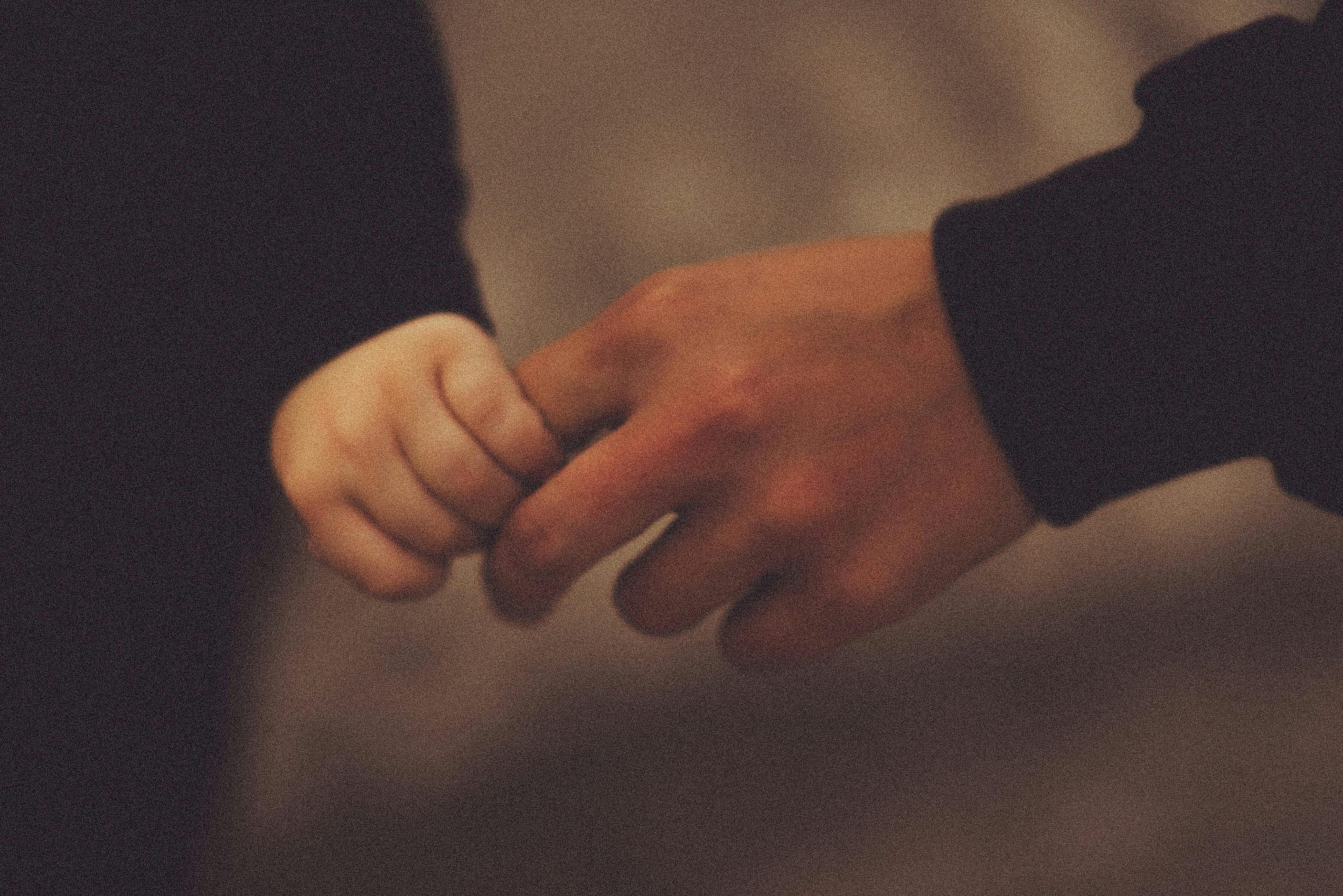Kisgyerek keze szorítja egy felnőtt ujját — a gyermekkori kötődés és az apa-gyermek kapcsolat szimbóluma